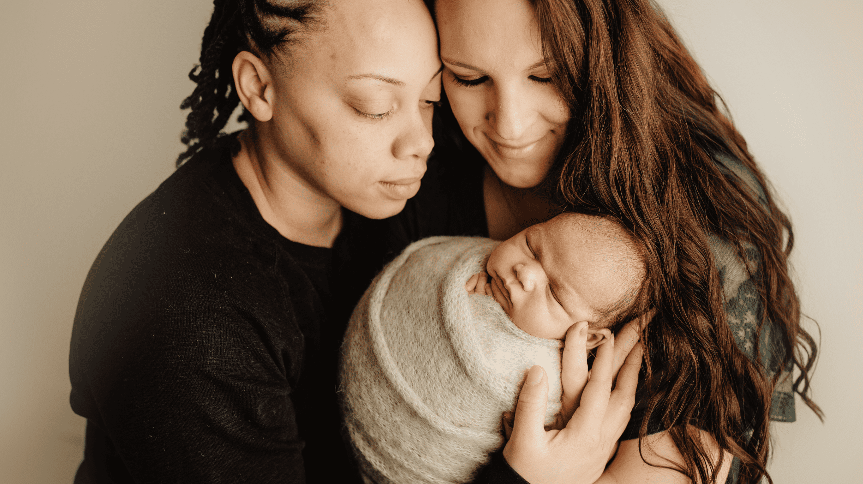Same Sex Female couple holding new born baby together